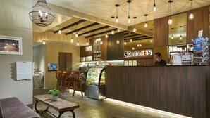 Een café interieur met een houten toonbank, hangende lampen en een vitrine.