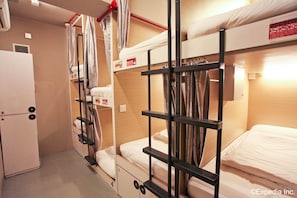 A compact hotel room with bunk beds, a small kitchenette, and a curtain for privacy. - K2 Guesthouse Central (Singapore)