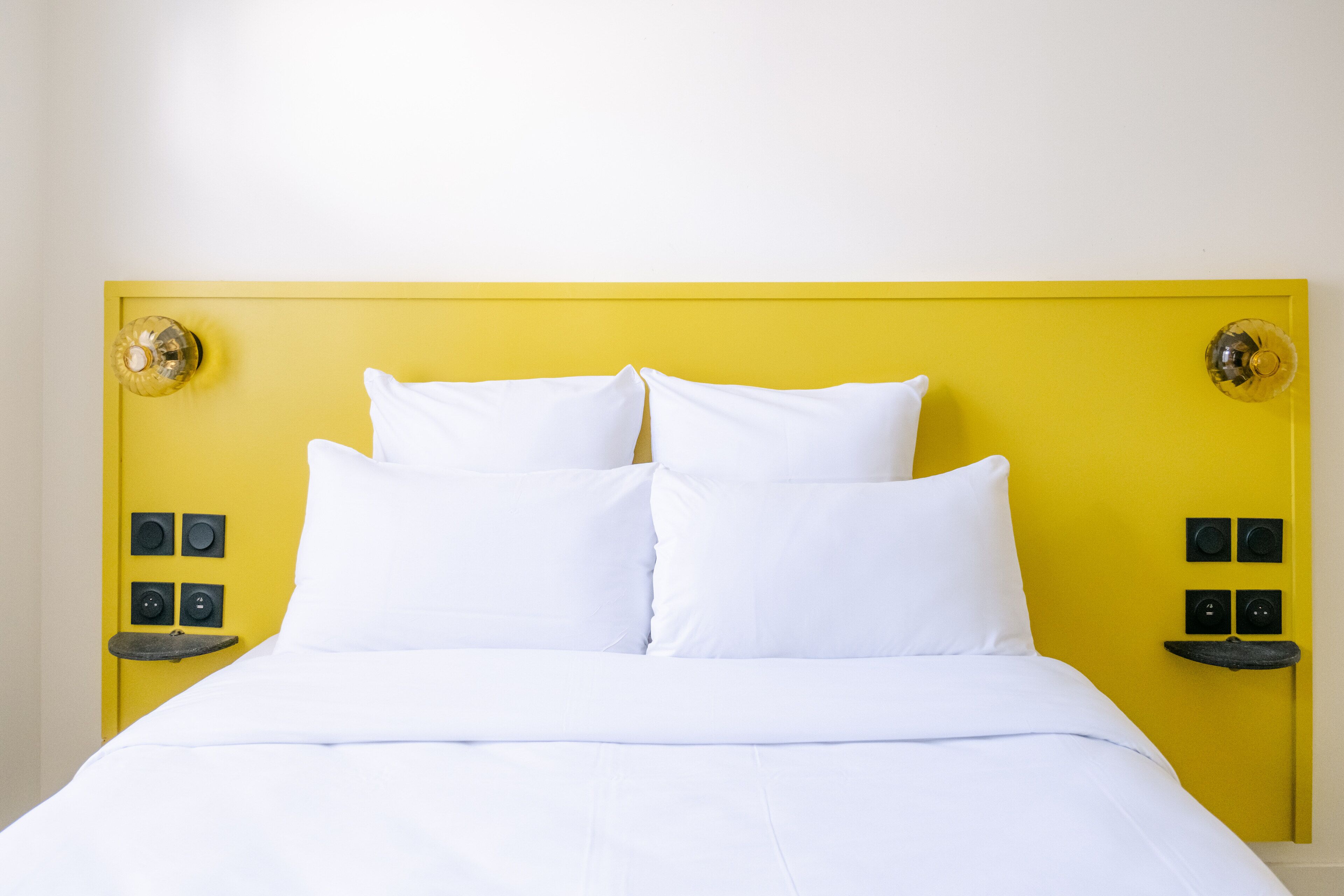 A bed with white bedding and a yellow headboard.