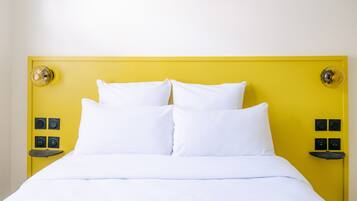 Una cama con ropa de cama blanca y un cabecero amarillo.