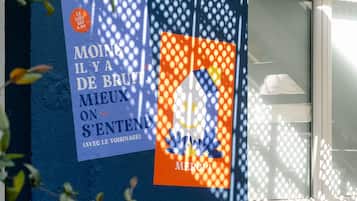 A building facade with a blue wall and a window. There are two posters on the wall, one with French text and another with a cartoon character.