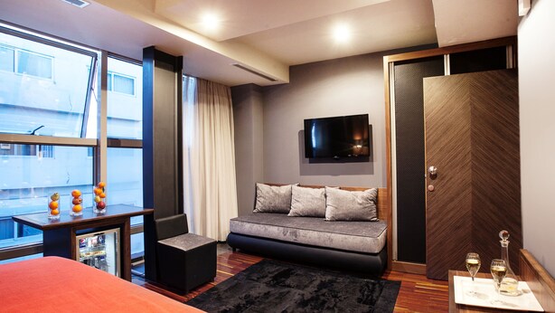 Ein modernes Hotelzimmer mit einem großen Bett, einer Sitzecke, einem Flachbildfernseher und einer Minibar.