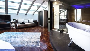 A modern living room with a large flat-screen TV, a sofa with cushions, a patterned rug, and a large window with skylights. - Diamond Suites (Thessaloniki)