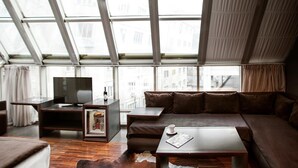 A modern living room with a large window, a sofa, a coffee table, and a TV. - Diamond Suites (Thessaloniki)