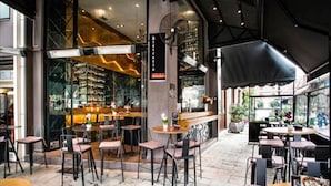 An indoor/outdoor cafe with tables and chairs, a bar area, and a view of the street. - Diamond Suites (Thessaloniki)