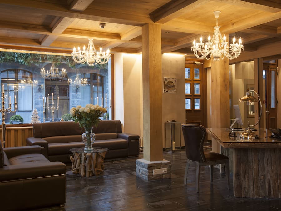 A spacious living area with leather sofas, a wooden coffee table, and a chandelier.