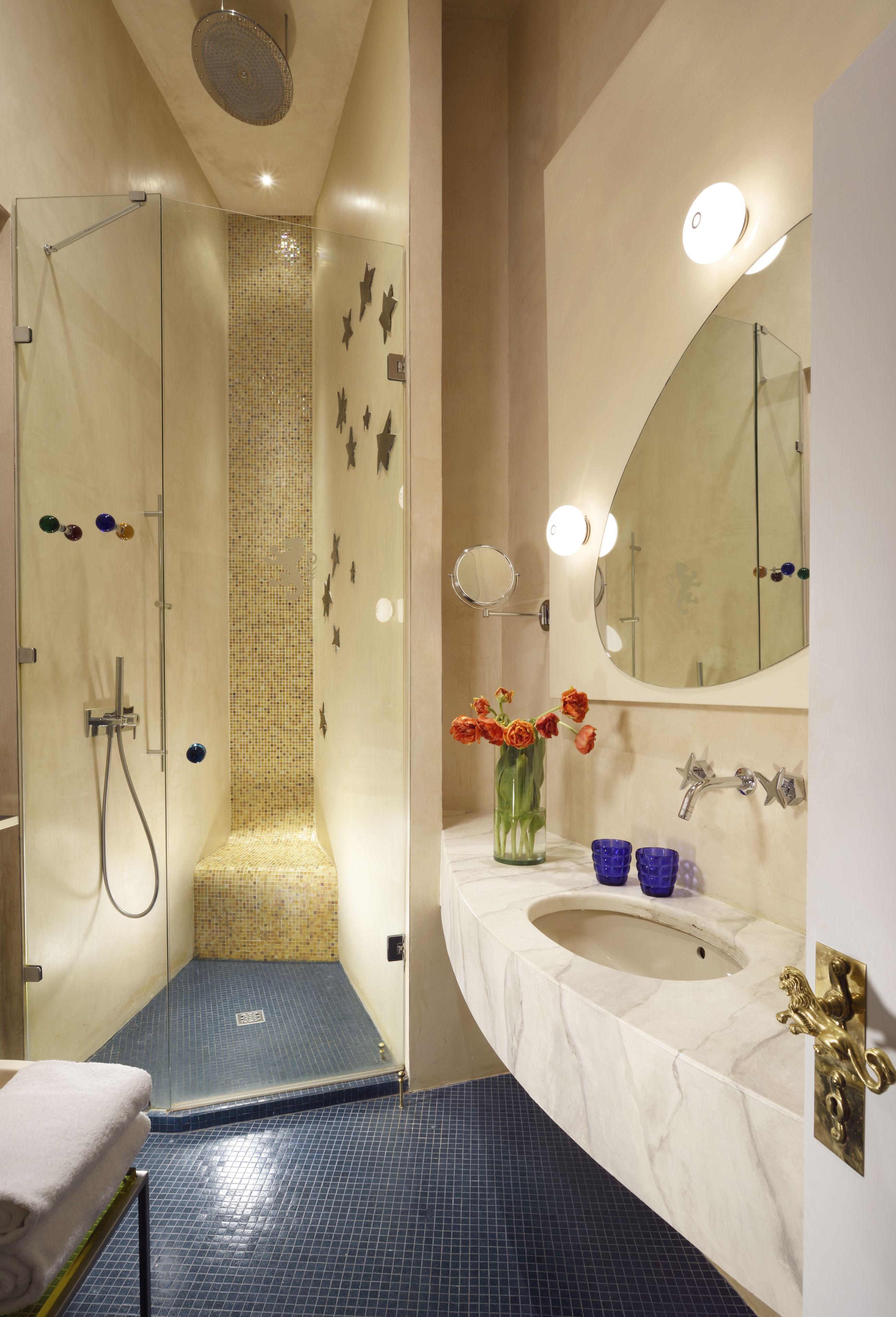 A modern bathroom with a glass-enclosed shower, a marble sink, and a mirror with lights.