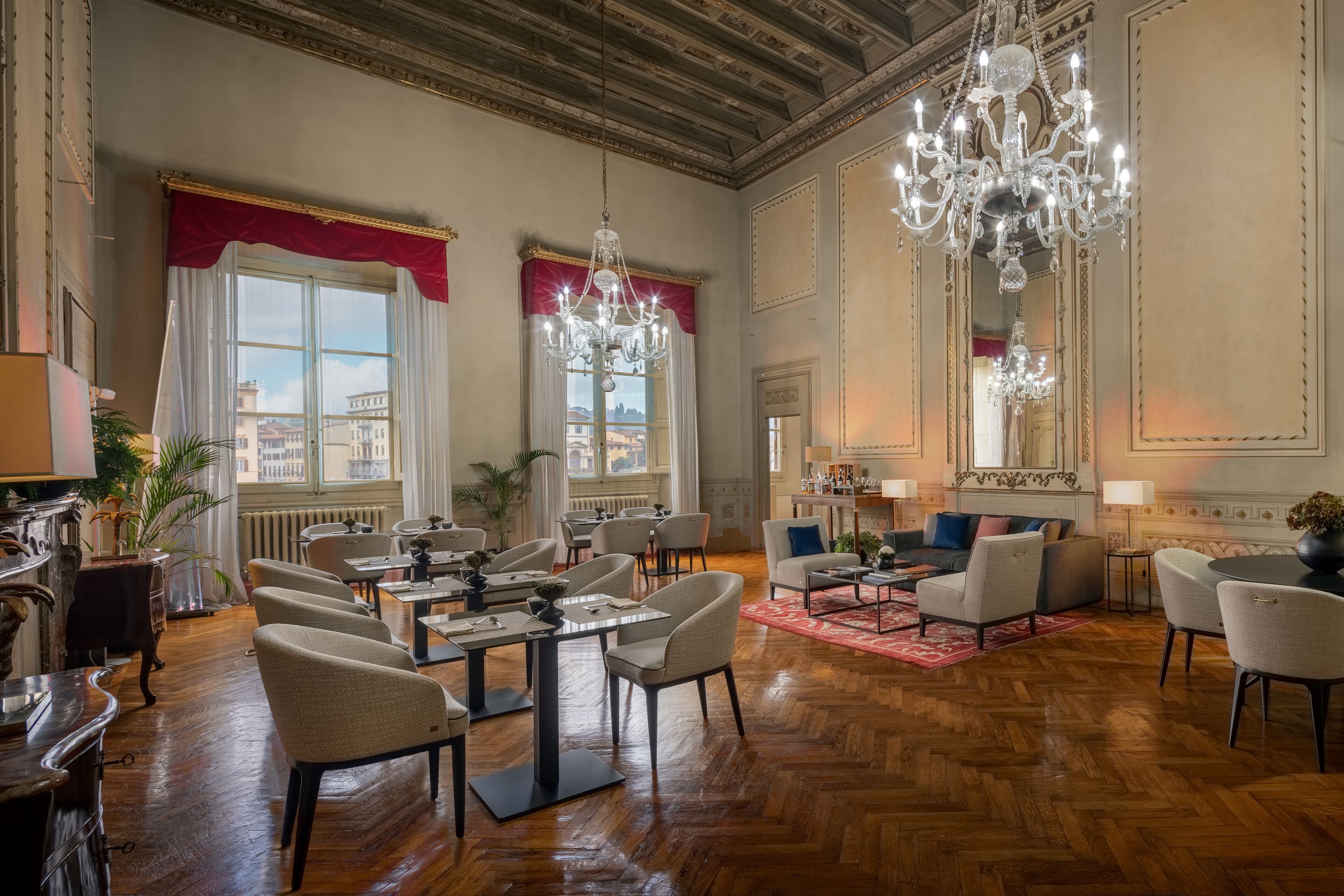 Een ruime hotellobby met hoge plafonds, kroonluchters en uitzicht op de stad door grote ramen.