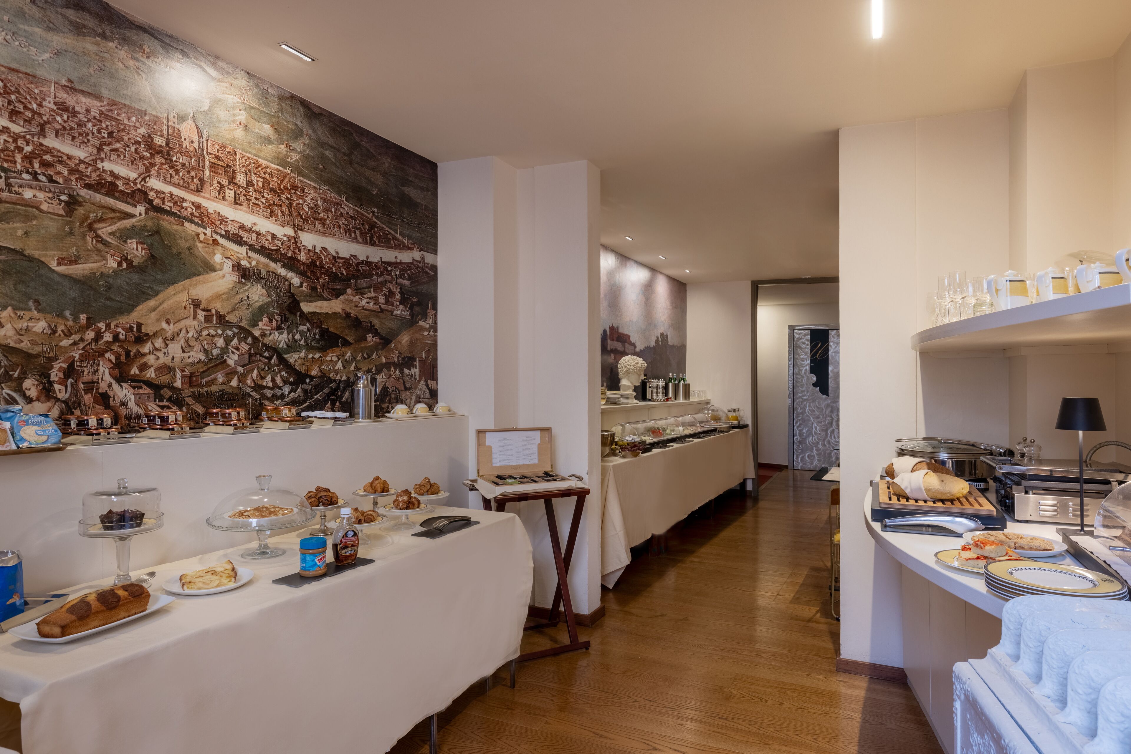 Un buffet de petit-déjeuner proposant une variété de plats et une grande fresque murale.