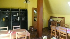 A compact kitchen with wooden cabinets and a dining area with a table and chairs. - Hotel Am Lindenhof (Hannover)