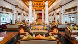 A spacious lobby with high ceilings, wooden beams, and a central seating area with sofas and armchairs. - Tawa Ravadee Resort, WorldHotels Distinctive (Si Maha Phot)