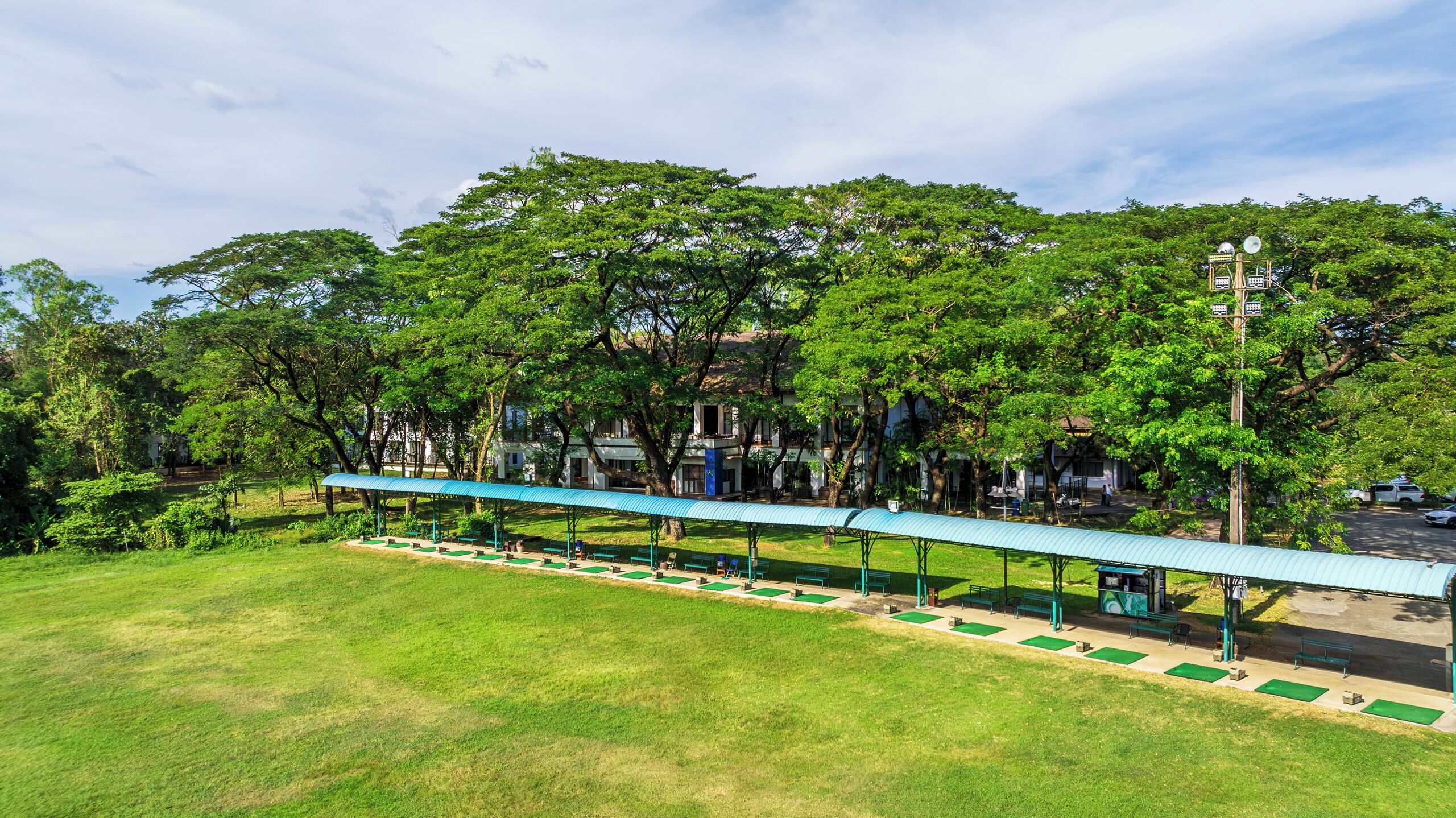 A park with a covered walkway, benches, and trees.