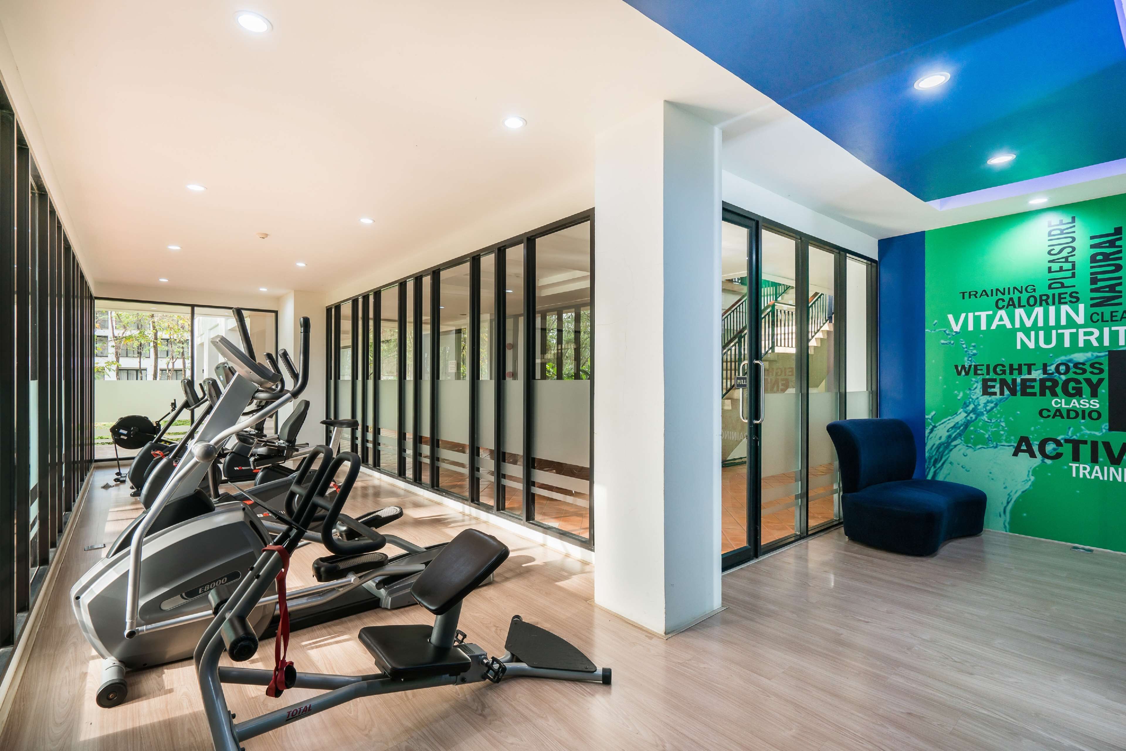 A gym with exercise equipment, a blue chair, and a wall with motivational words.