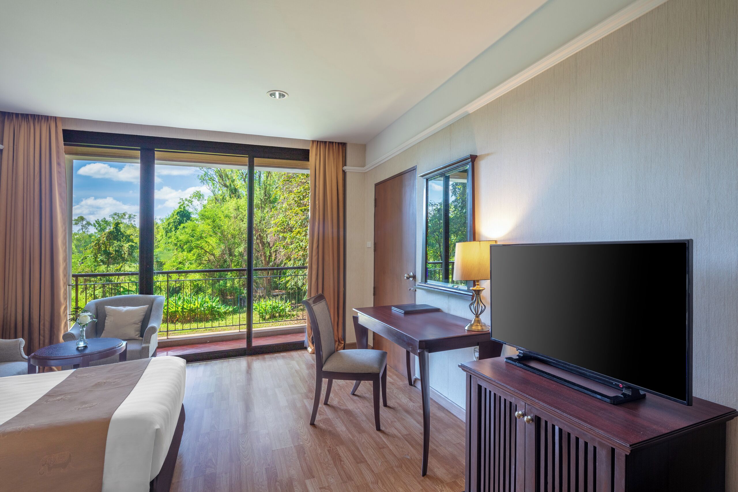 A hotel room with a large window, a bed, a desk, a chair, and a television.