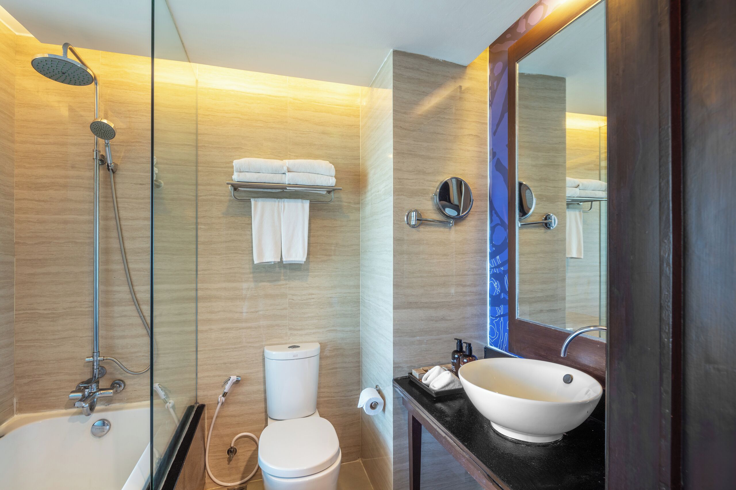 Ein modernes Badezimmer mit einer Duschkabine aus Glas, einer Toilette, einem Waschbecken mit großem Becken und einem Spiegel.