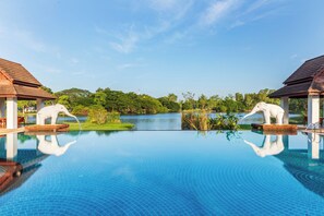 Una piscina al aire libre, sombrillas, sillones reclinables de piscina