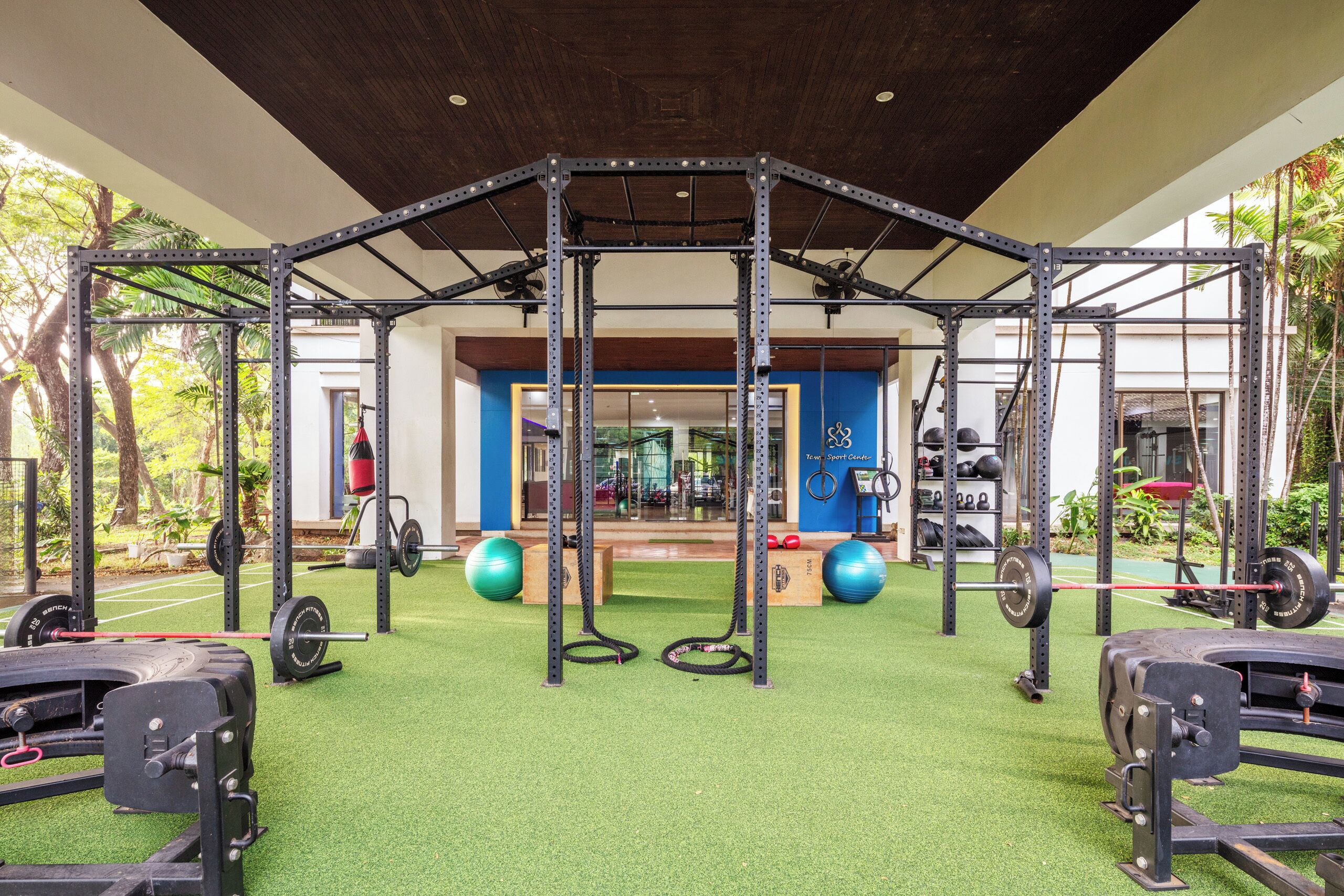 Une salle de sport équipée d’une structure pour faire de la traction, de matériel de musculation et de ballons d’exercice.
