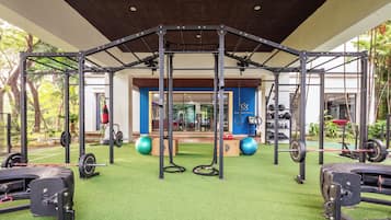 Une salle de sport équipée d’une structure pour faire de la traction, de matériel de musculation et de ballons d’exercice.