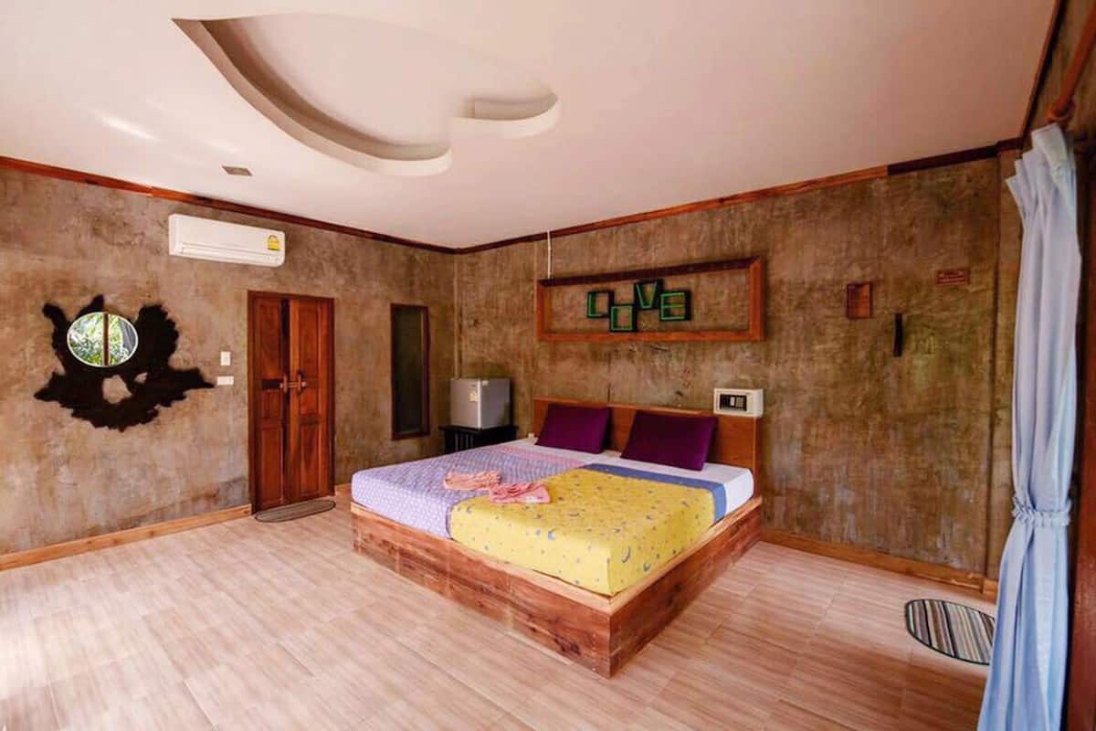 Ein Schlafzimmer mit einem hölzernen Bett, einem Deckenventilator, einer Wandklimaanlage und einem gerahmten Kunstwerk.
