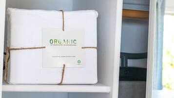 A white shelf with a white package tied with twine, labeled "ORGANIC 100% ORGANIC COTTON 100% COTON BIOLOGIQUE QUEEN SHEET ENSEMBLE DE DRAPS LIT GRAND."
