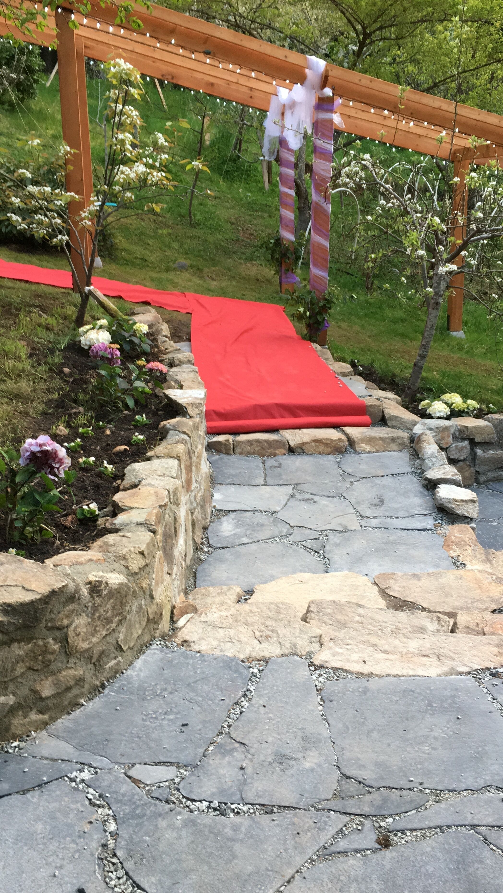 A stone pathway leading to a wooden pergola with string lights.