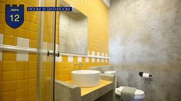 Un baño con azulejos amarillos, un lavamanos blanco y un inodoro.
