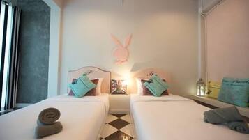 Habitación de hotel con dos camas, un conejo decorativo en la pared y suelo a cuadros.