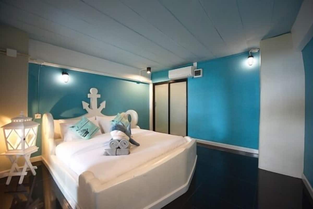 Quarto com cama, mesa de cabeceira, ar-condicionado fixado na parede e uma âncora decorativa.
