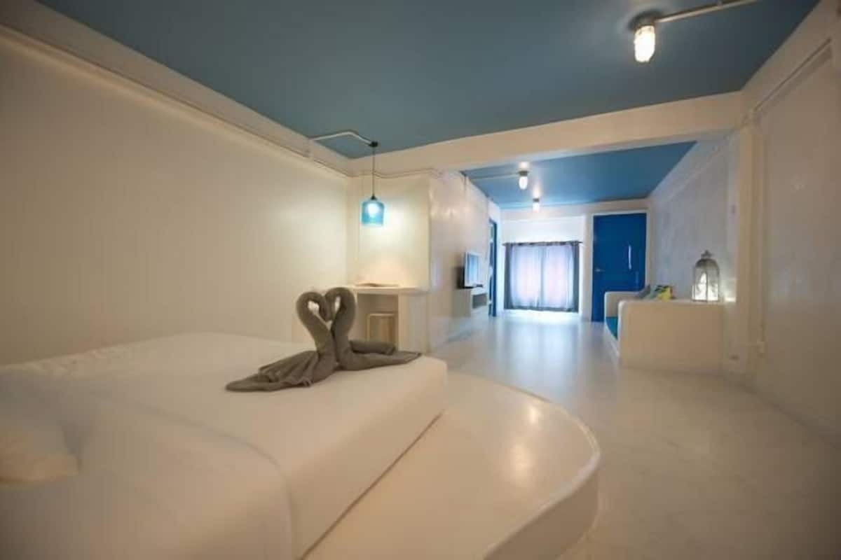 Quarto de hotel moderno com uma cama grande, uma escrivaninha e vista para o quarto vizinho.