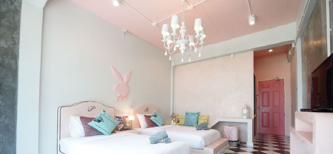 A bedroom with two beds, a chandelier, a pink door, and a checkered floor.