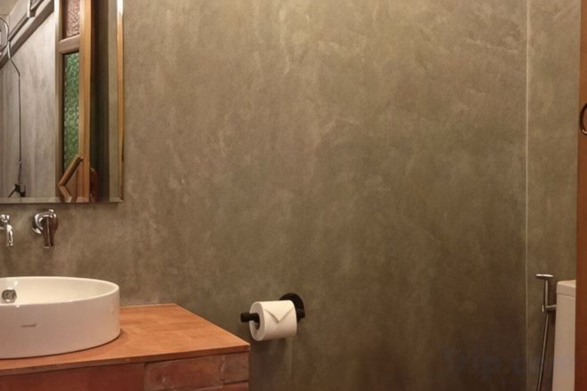 Un baño con un lavabo redondo, un espejo y un dispensador de papel higiénico.
