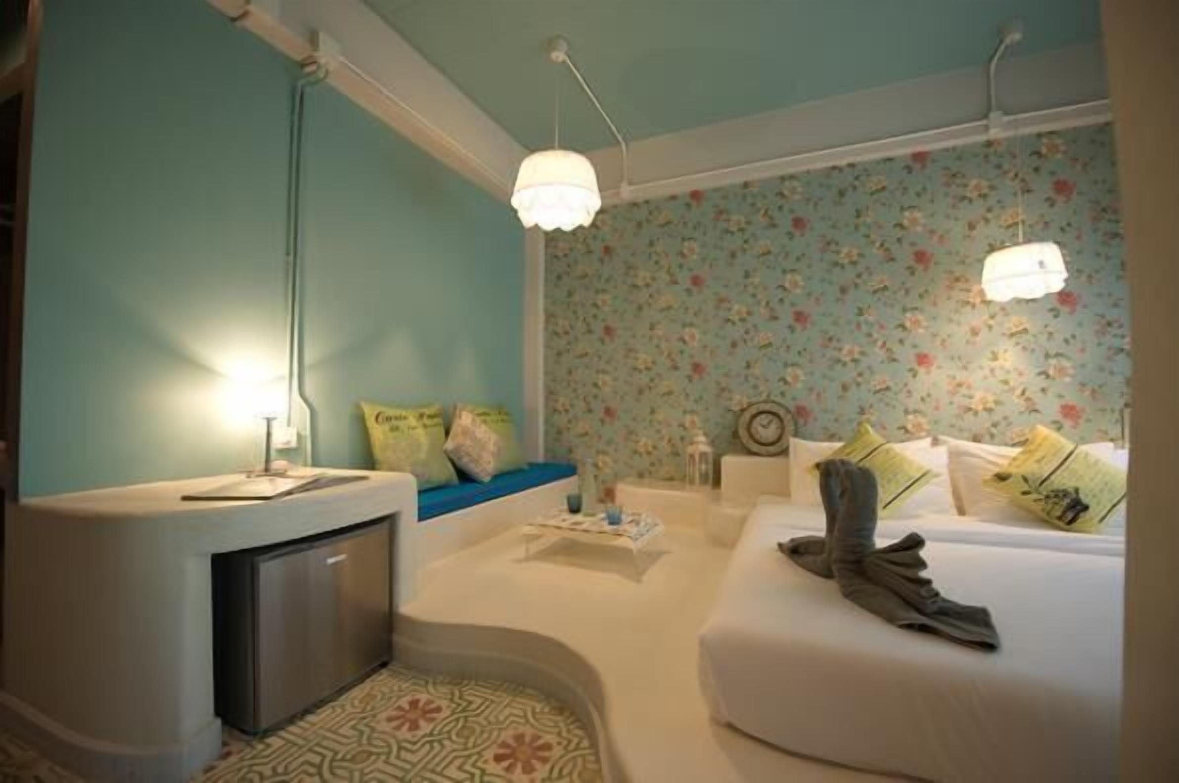 A hotel room with a curved bed, a small desk, and a kitchenette.