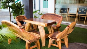 A wooden outdoor seating area with a table and chairs, surrounded by artificial grass and a stone pathway. - Orkid Inn Mahkota Cheras (Cheras)