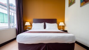 A neatly made bed with white linens and a dark headboard in a room with a wooden floor and a window with curtains. - Orkid Inn Mahkota Cheras (Cheras)