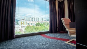 A hotel room with a large window, a red carpet, and a modern chair. - Orkid Inn Mahkota Cheras (Cheras)