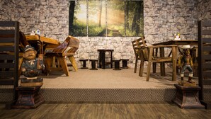 A rustic room with stone walls, a large forest painting, wooden furniture, and a bear statue. - Orkid Inn Mahkota Cheras (Cheras)