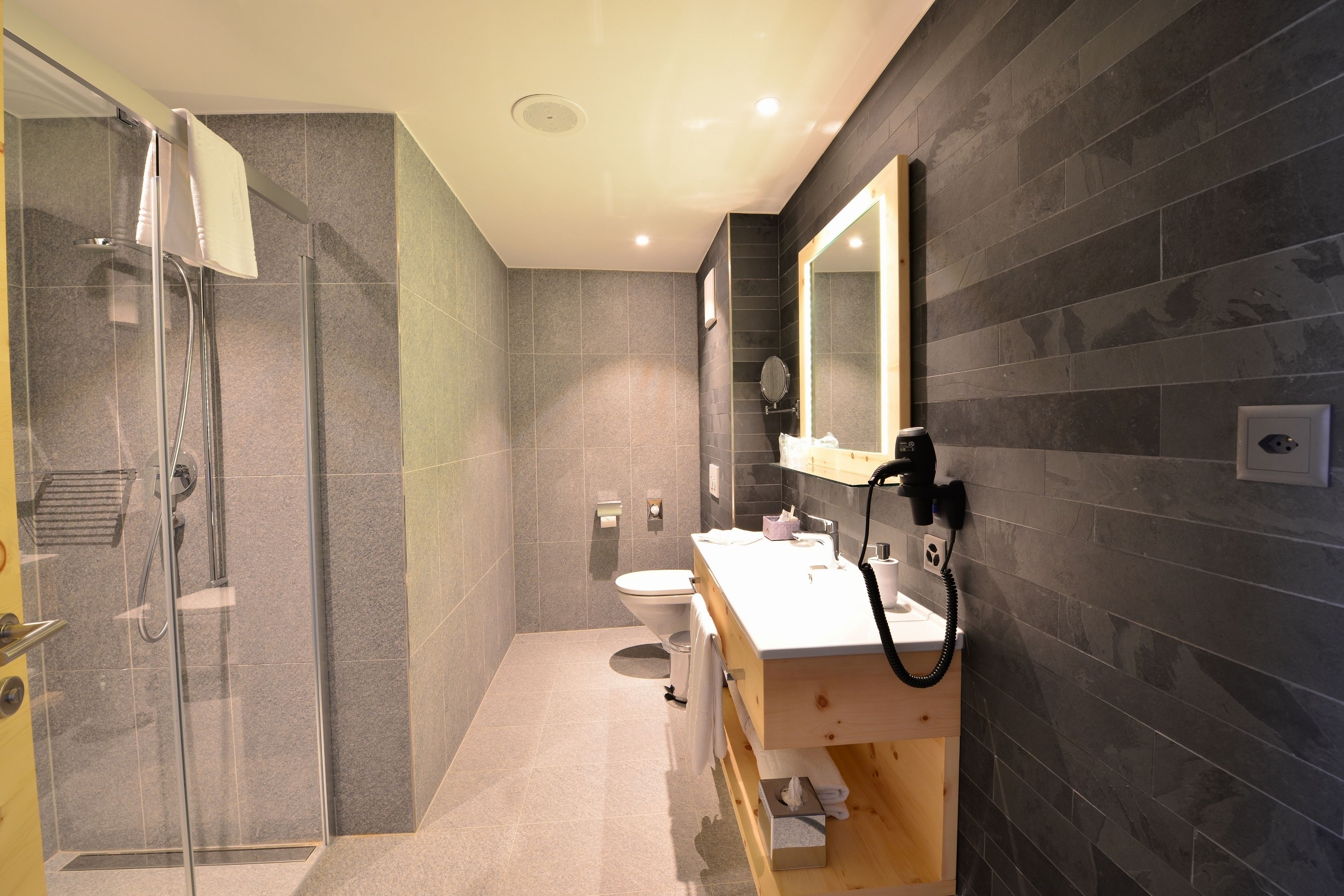 Un baño moderno con cabina de ducha de vidrio, inodoro y tocador con espejo.