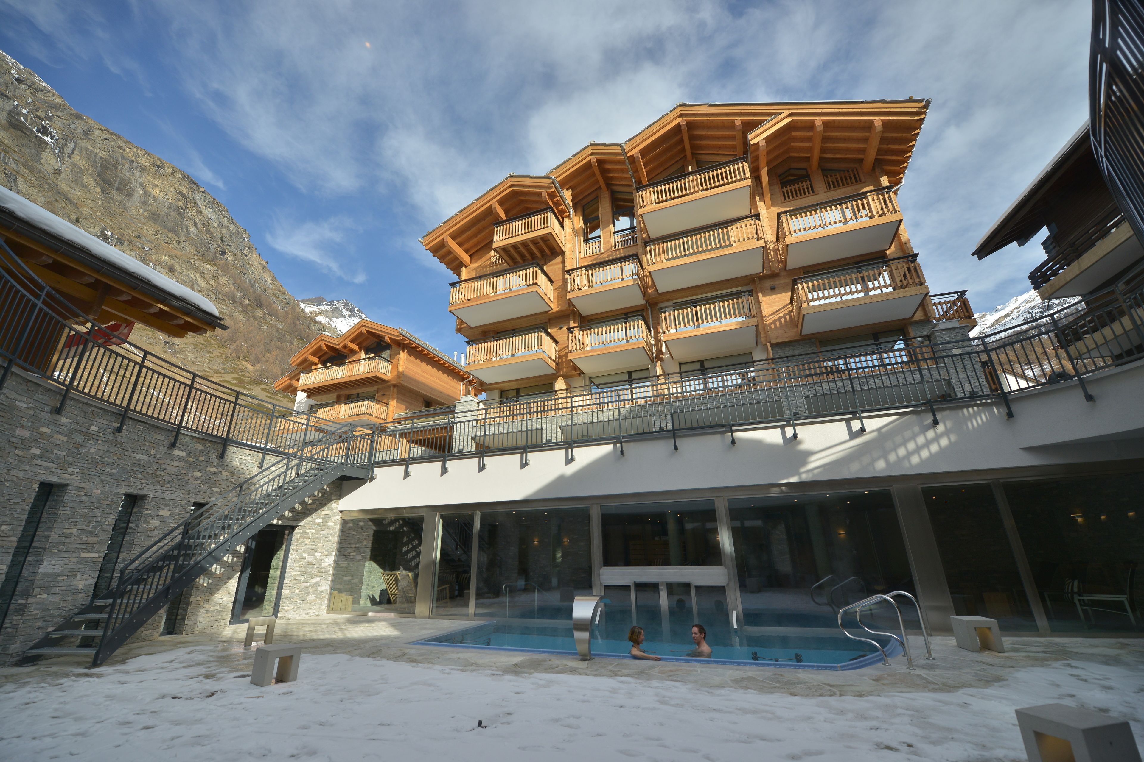 Un edificio a più piani con balconi, una piscina e un paesaggio innevato.