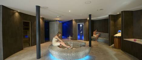 A modern spa area with a circular seating area, a reception desk, and a large pillar.