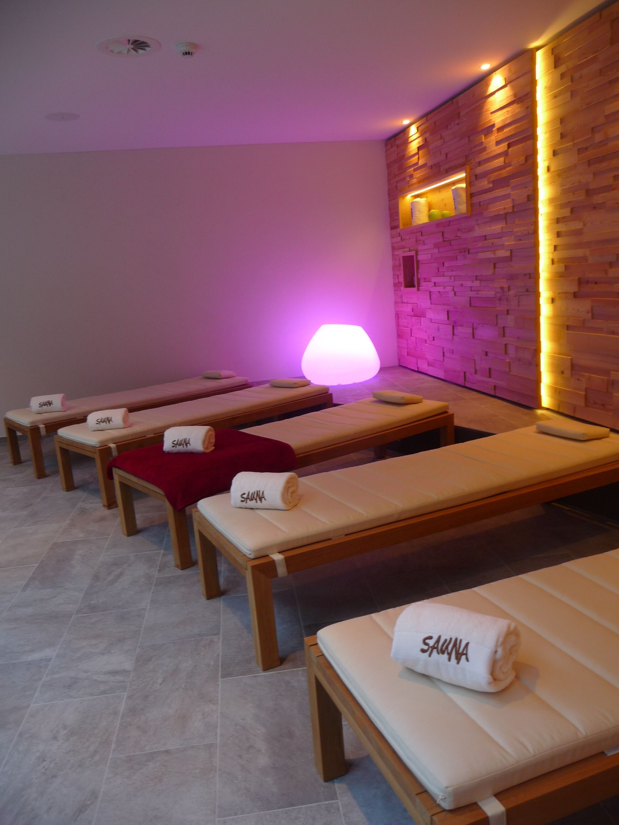 A spa room with multiple wooden massage tables, each with a towel labeled "SAUNA".