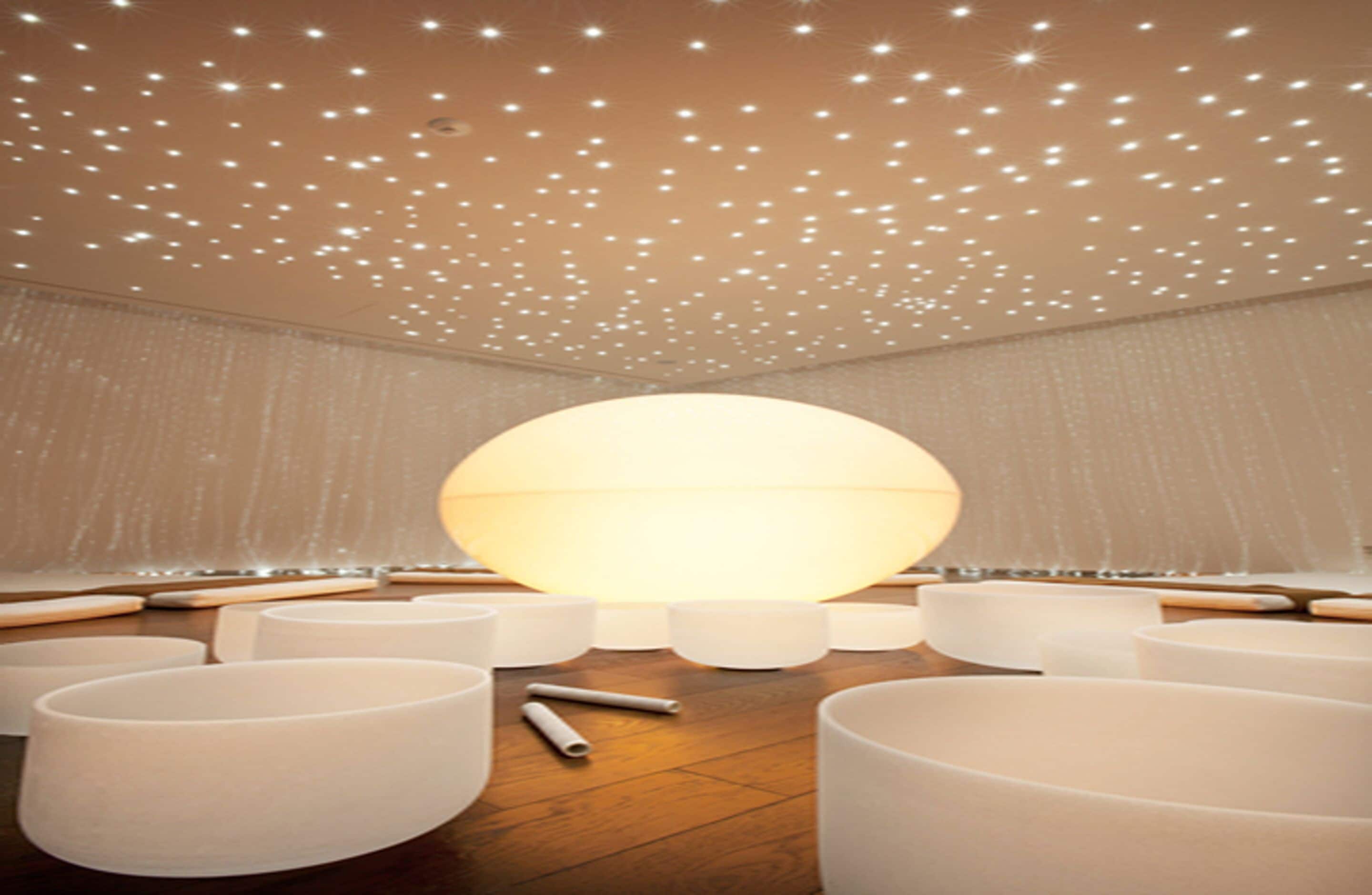 Une pièce dotée d’un grand luminaire sphérique au centre, entouré de plusieurs espaces de détente de forme cylindrique.