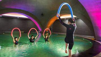An indoor swimming pool with four people performing with hoops.