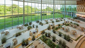 Un espacio interior amplio con ventanas grandes, diversas opciones de asientos y vistas a un paisaje verde.