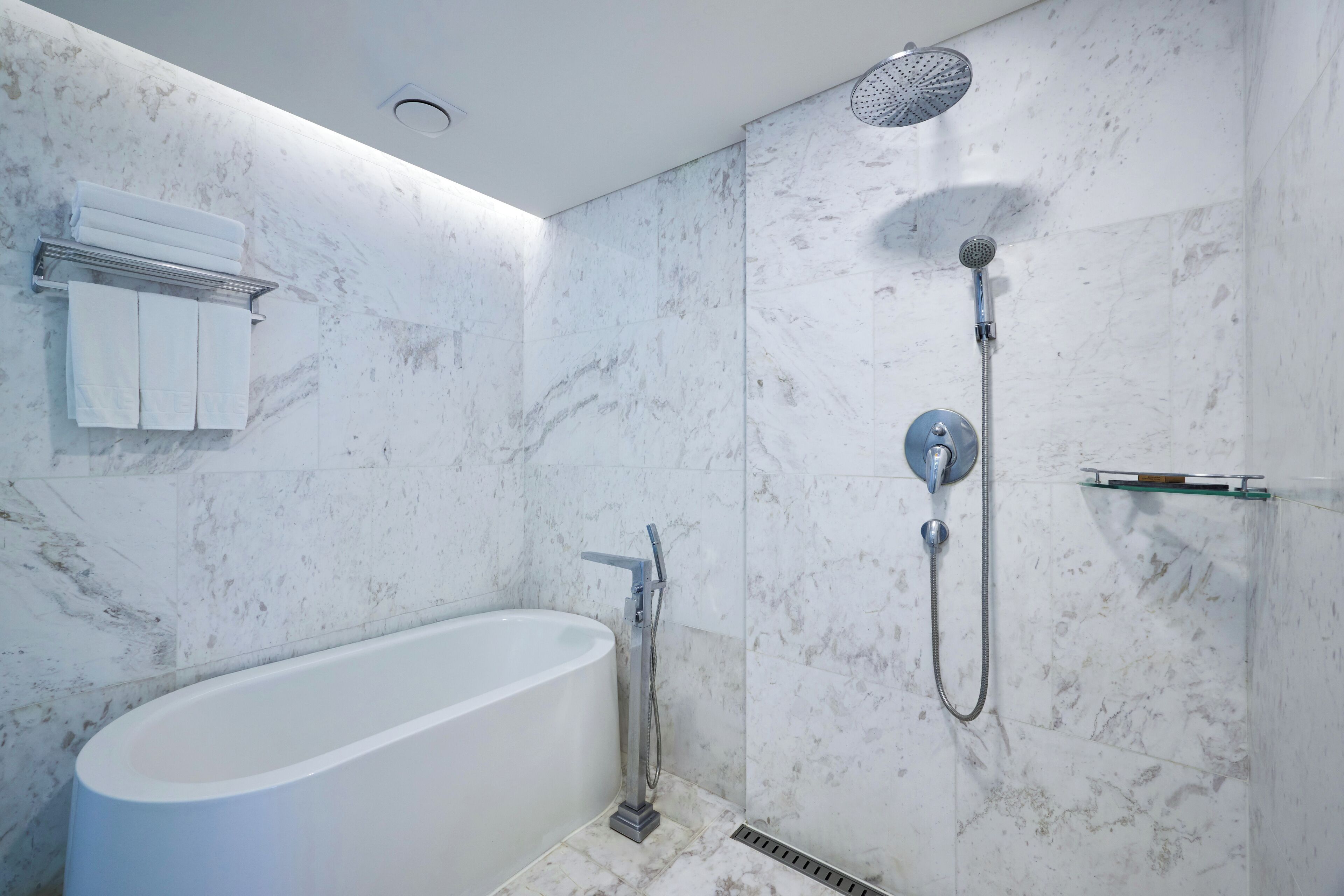 A modern bathroom with a freestanding bathtub, a showerhead, and a towel rack.