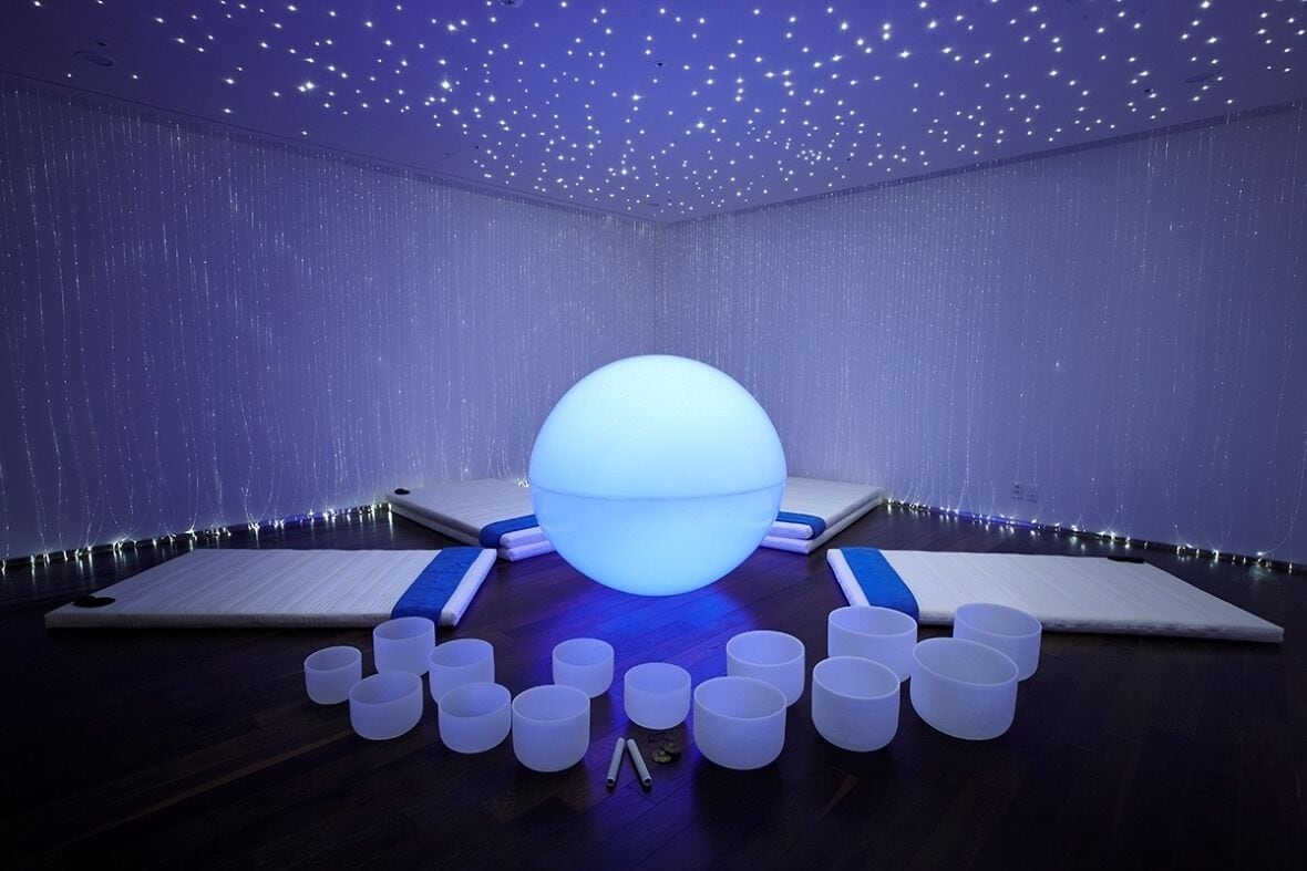 A room with a large illuminated sphere, multiple white cylindrical objects, and a starry ceiling.
