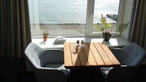 A room with a view of the sea, a wooden table, two chairs, and potted plants. - Hotel De Belgische Loodsensociëteit (Vlissingen)
