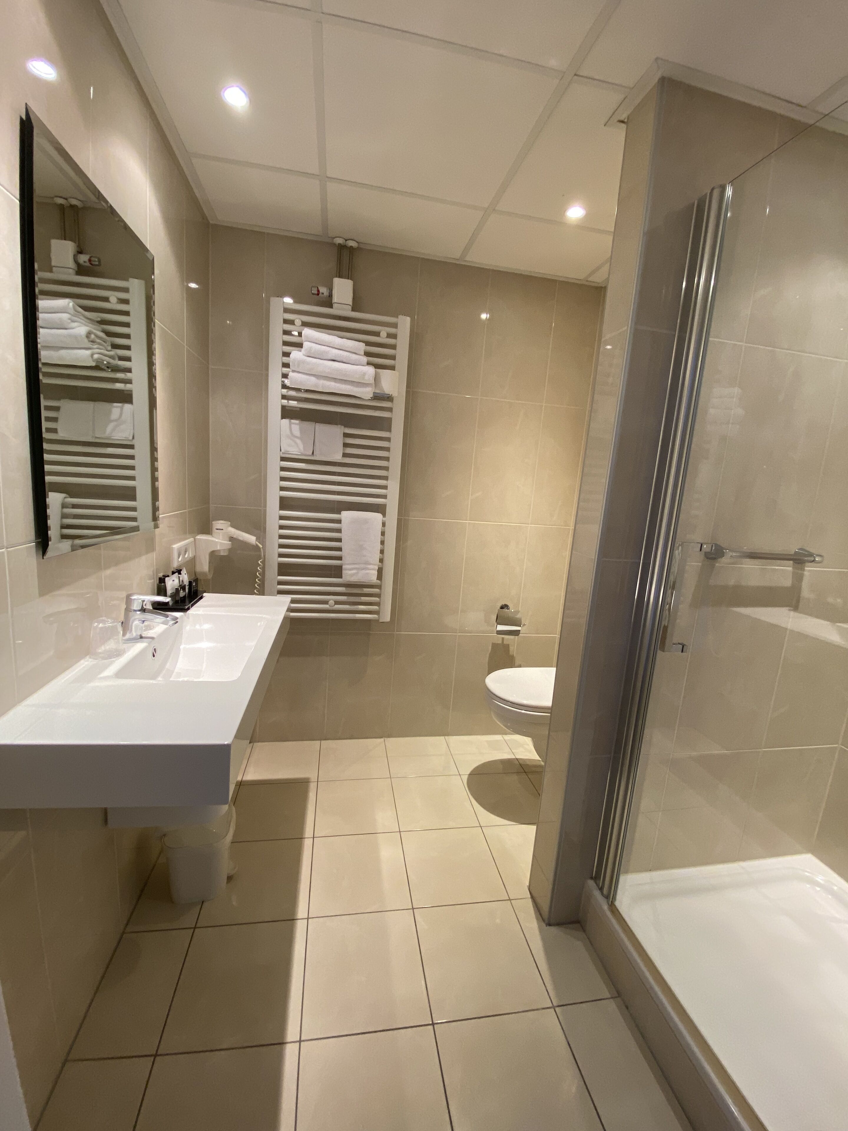 A modern bathroom with two sinks, a glass shower enclosure, and a toilet.