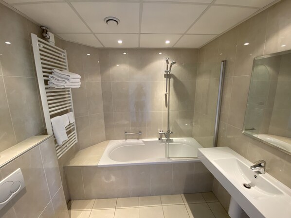 Un baño moderno con bañera, ducha y un espejo grande.