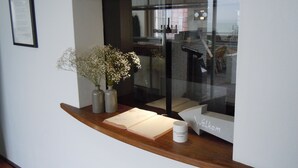 A reception desk with a welcome sign, a framed document on the wall, and two vases with flowers. - Hotel De Belgische Loodsensociëteit (Vlissingen)