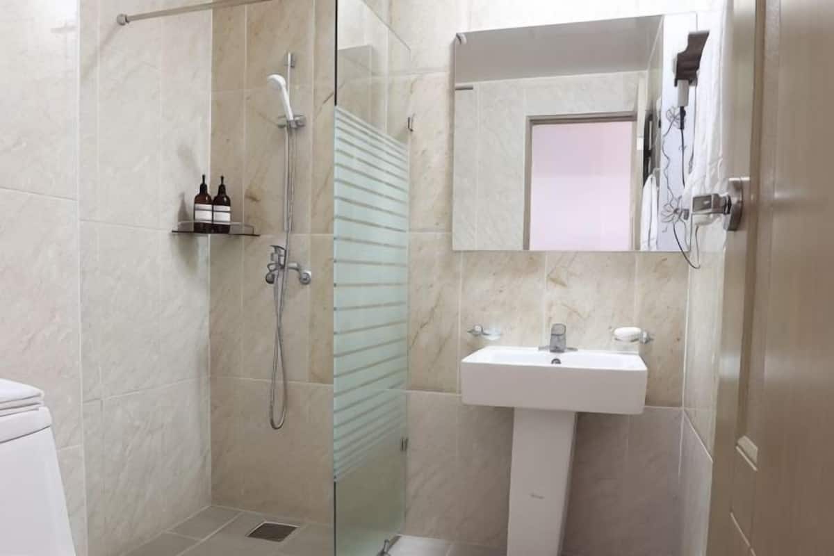 A bathroom with a glass-enclosed shower, a white sink, and a mirror above it.